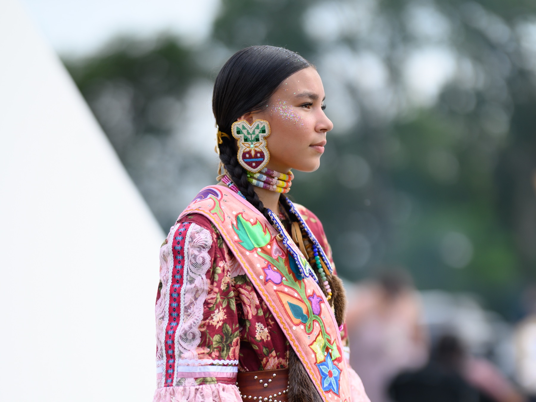 Close portrait of Valerie Leith in profile, wearing beaded earrings and braids