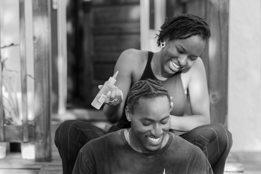 Gomoson Wonosikou working oil into her brother Joshua's hair on the steps, both laughing