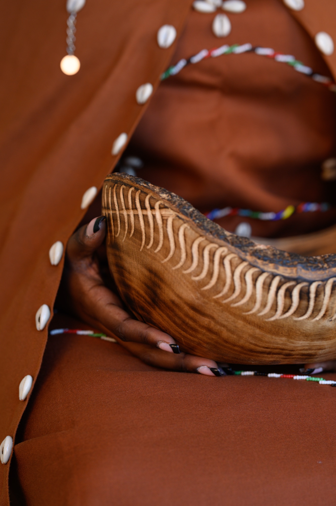 Detail of the carved wooden bowl and cowrie shells in Lizzy Nyoike's Kikuyu regalia