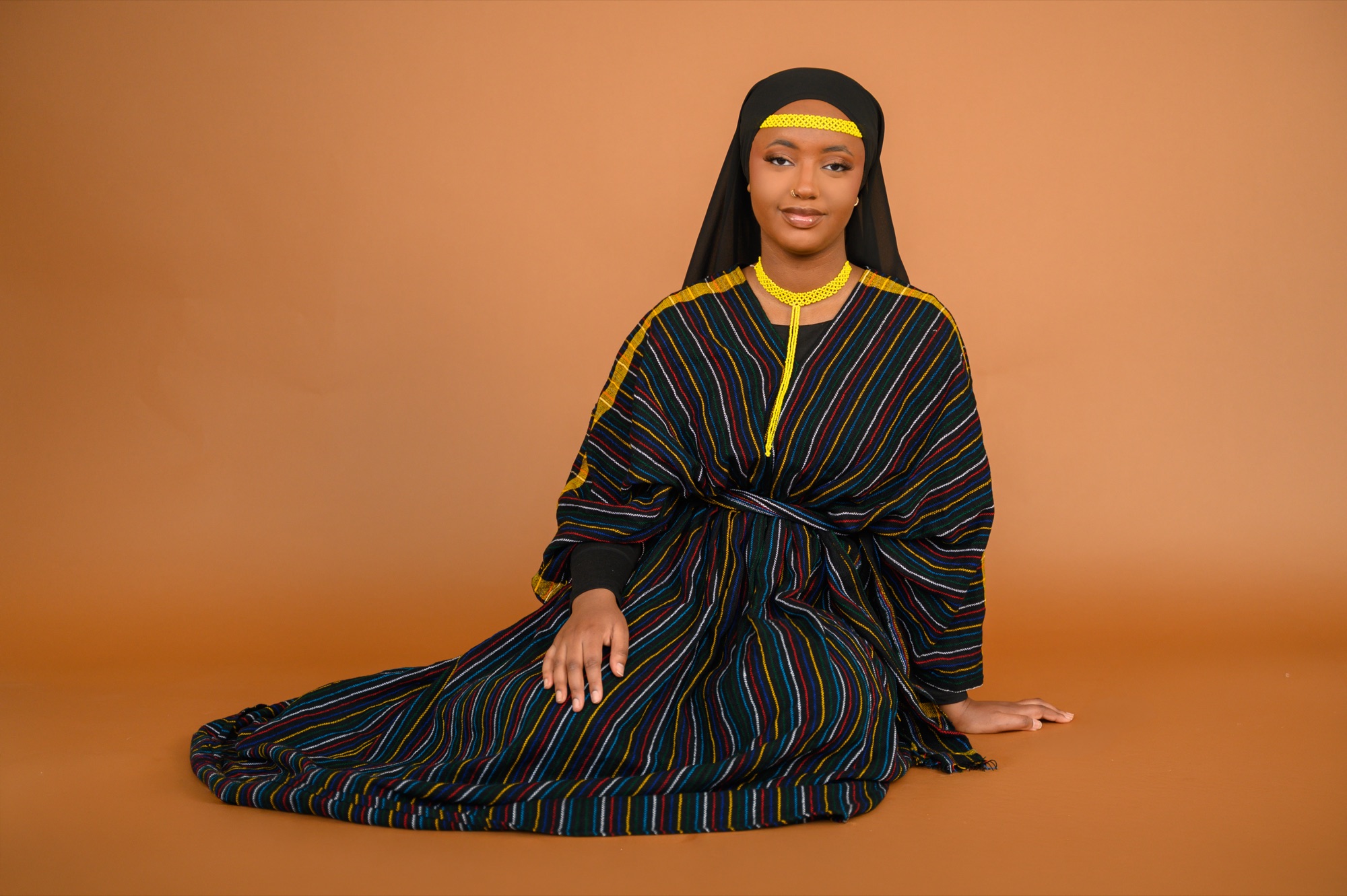 Faaya Adem seated in an Oromo aadaa dress and callee beadwork