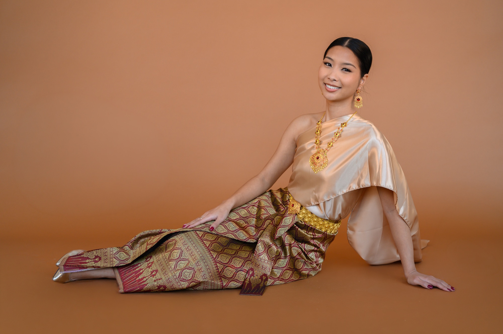 Meena Saechao seated in the Chut Thai Chakri, gold brocade shawl across one shoulder