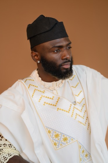 Close profile portrait of Nelson Igbinovia in a white agbada and black cap