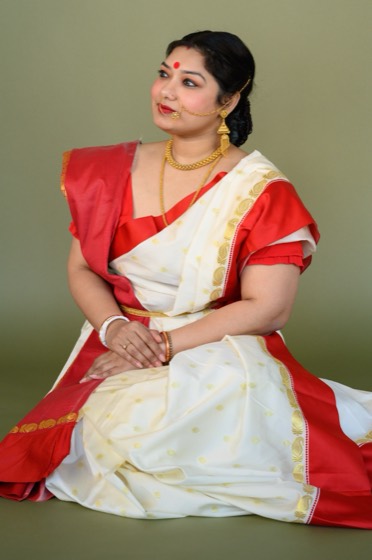Debanjana Chatterjee seated in a white Garad saree with a red border