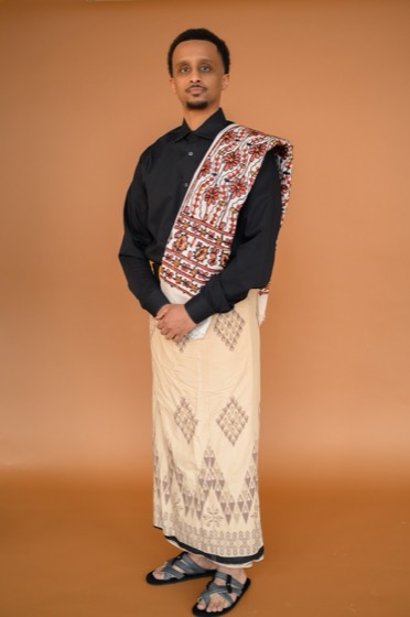 Mohamoud O. Mohamed standing in a macawis with a woven shawl across his shoulder